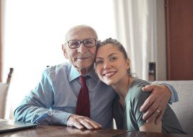 an older man side-hugging a younger woman